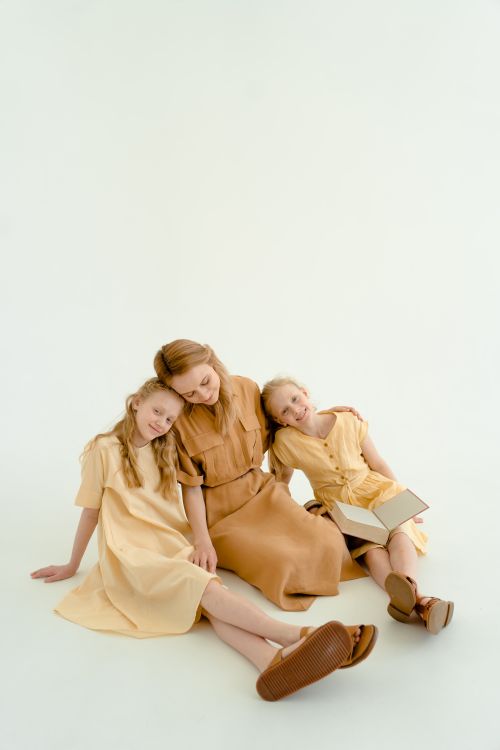 Free Charming studio portrait of a mother with her two daughters sitting and reading together. Stock Photo