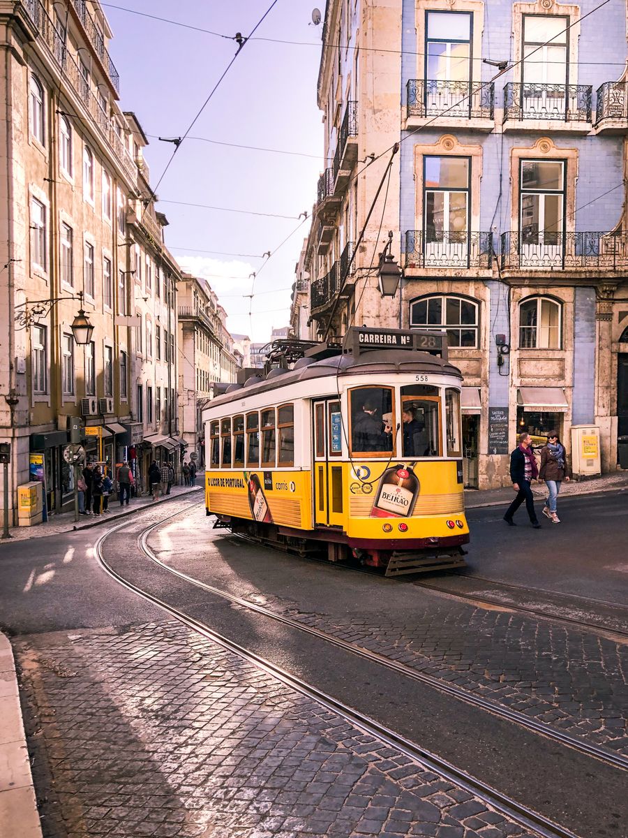 A vintage yellow tram passing the Estrela Basilica in Lisbon, Portugal