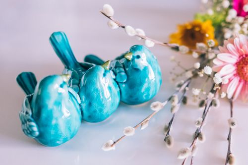 Free Three turquoise bird figurines surrounded by colorful blossoms create a vibrant decorative scene. Stock Photo