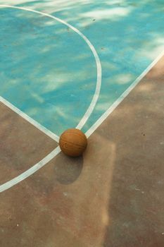 A basketball on a sunlit court, highlighting the sport's daytime ambiance.