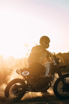 An adventurous motorcyclist rides through the dust during a captivating sunset.
