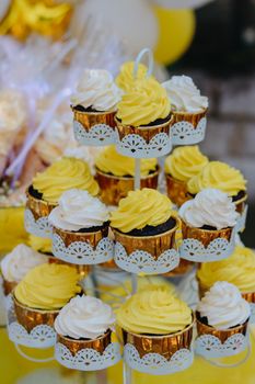 Delightful cupcake display with yellow and white frosting on a decorative stand, perfect for parties.