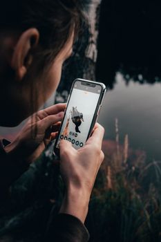 A person uses a smartphone to capture a duck by the pond in an artistic composition.