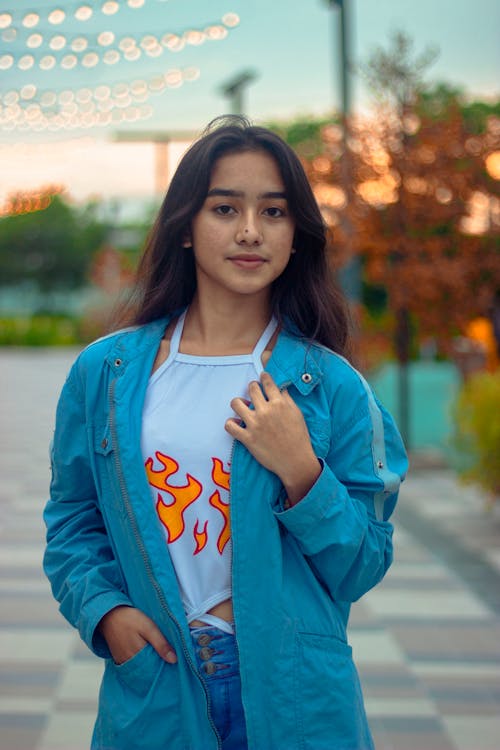 A Pretty Young Woman Wearing a Blue Jacket Over a White Tank Top