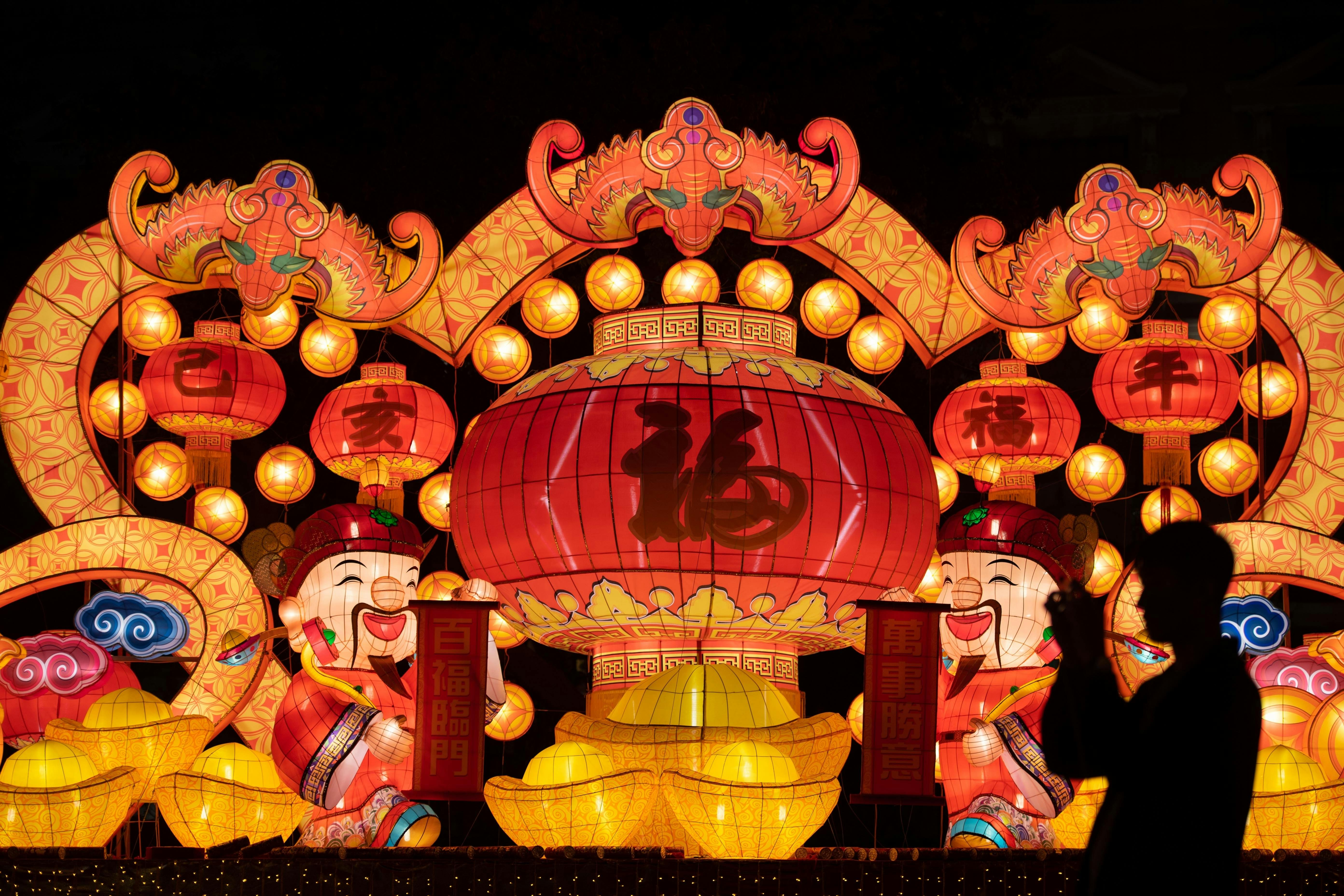 A vivid array of Chinese lanterns beautifully illuminated during a night festival with silhouetted onlooker.