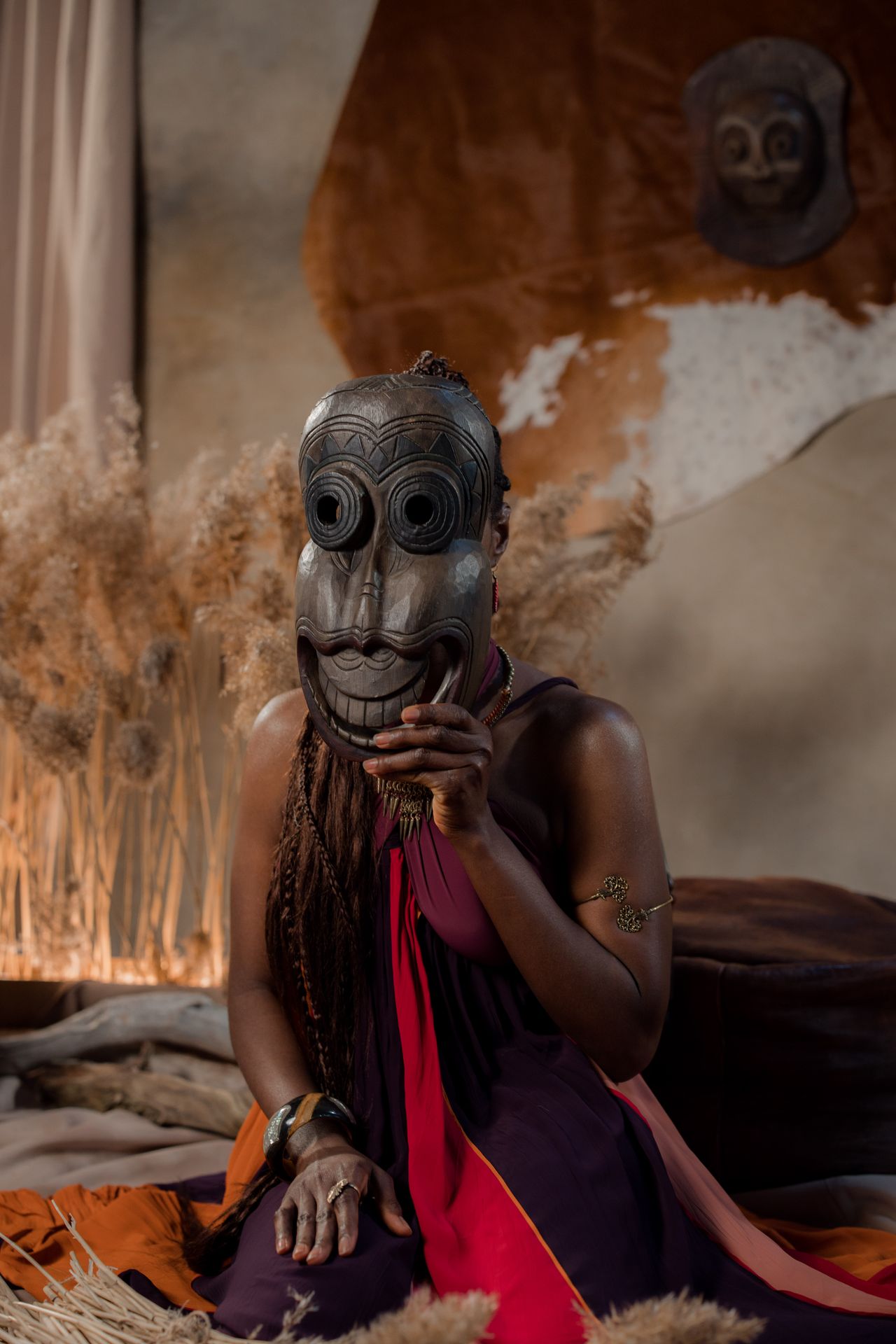 Hand-carved African wooden mask styled with a cowhide and dried grasses