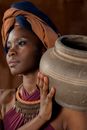 Woman in Orange and Blue Turban Holding Brown Clay Pot