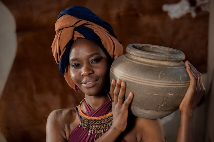 Woman Wearing Head Wrap Holding Gray Clay Pot