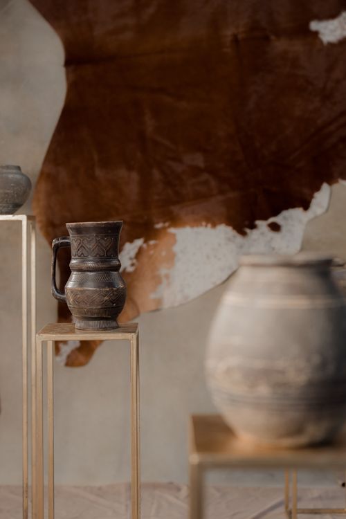 Free Artistic arrangement of ceramic jars and jugs on wooden stands in an indoor studio setting. Stock Photo