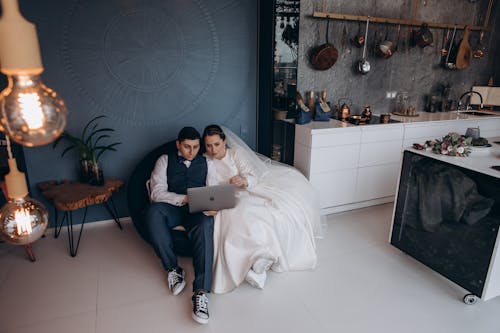 Free Bride and Groom Sitting While Looking at the Laptop  Stock Photo