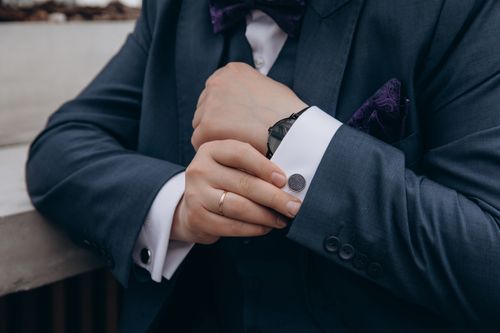 Free Close-up of a man adjusting his suit jacket cuff with a watch and ring visible, showing elegance. Stock Photo