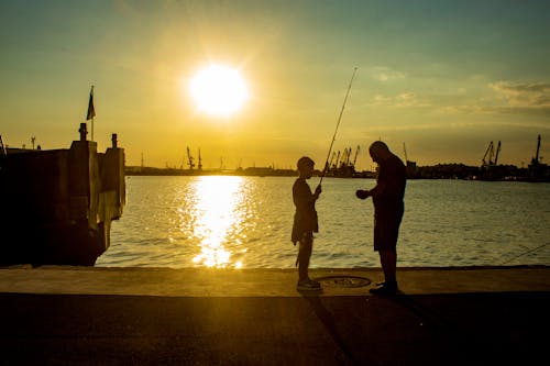 Free A Boy Holding a Fishing Rod in Front of a Man Stock Photo