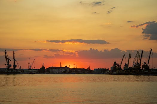 Stunning sunset over a port with cranes silhouetted against the vibrant sky.