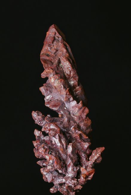 Fotomural Toma vertical detallada de una muestra mineral irregular contra un fondo negro.