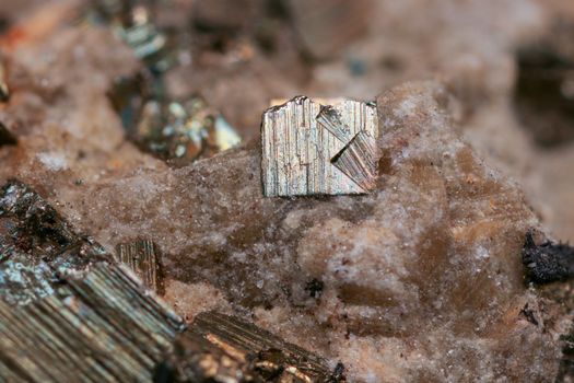 Detailed close-up of pyrite crystal on rocky surface, showcasing natural textures and colors.