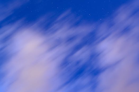 Abstract view of a night sky featuring blurred clouds and distant stars, creating a dreamy effect.