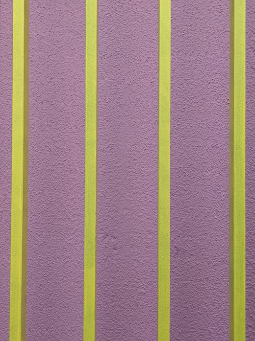 Free Vibrant green and purple vertical stripes create a modern abstract design on a textured wall. Stock Photo