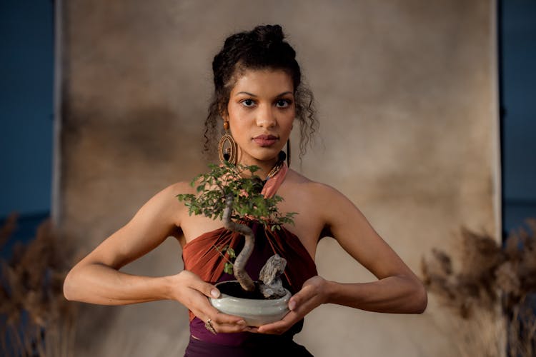 A Woman Holding A Bonsai Plant