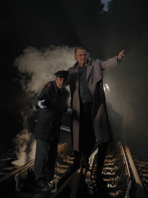 Free Two senior men on railway tracks amidst steam, pointing into darkness. Stock Photo