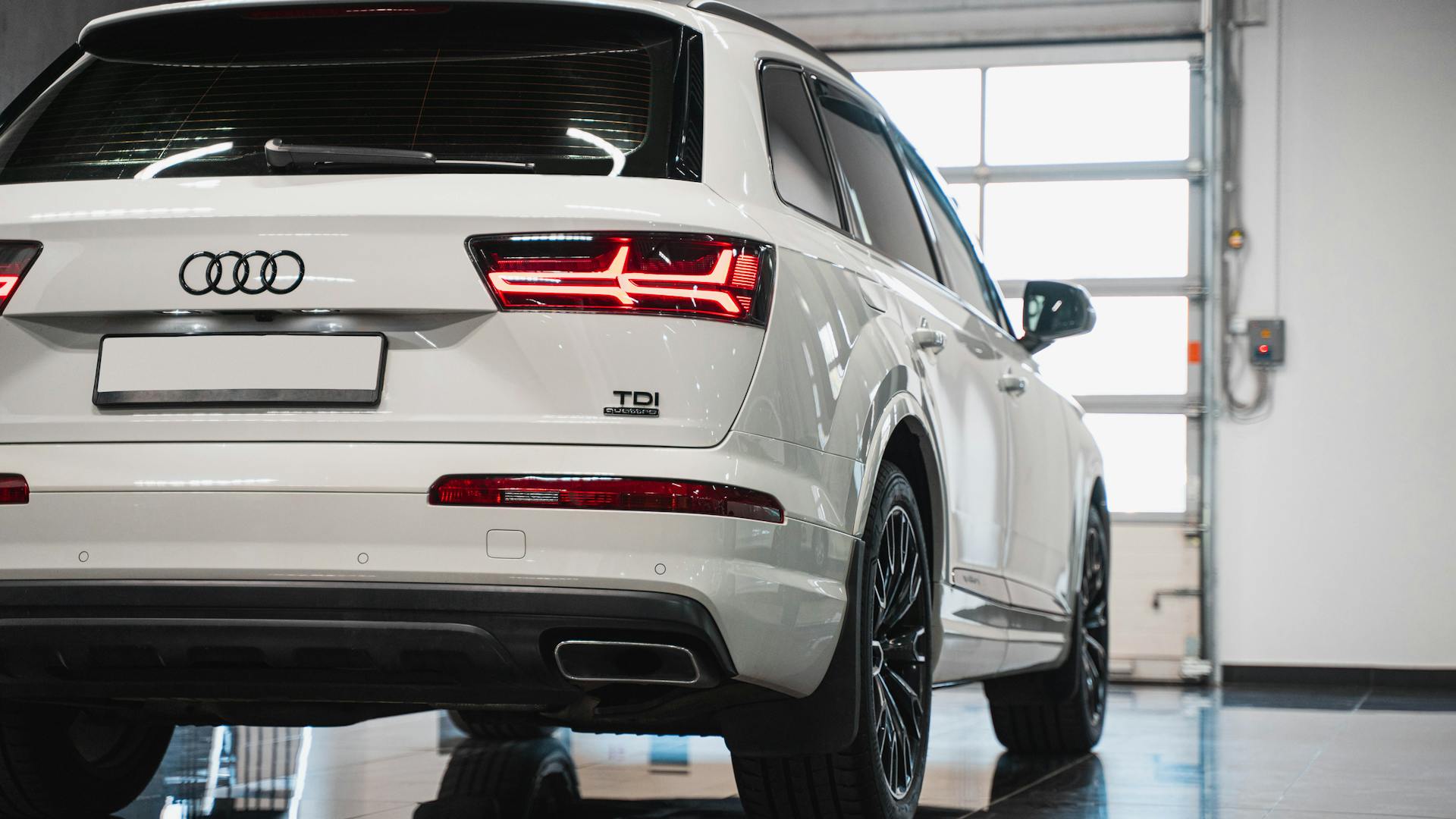 Close-up of a white luxury SUV with Audi emblem and sleek design in a modern showroom.