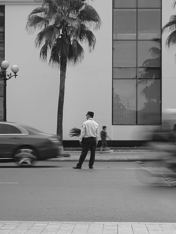 A Traffic Aide Standing on the Street Near a Vehicle
