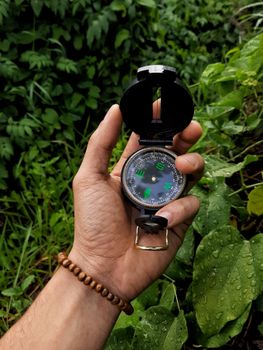 A person holding a compass in a lush outdoor setting, perfect for adventure and navigation themes.