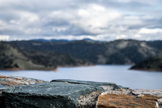 在多云的天空下，湖泊和岩石构成前景，呈现出令人惊叹的山地景观