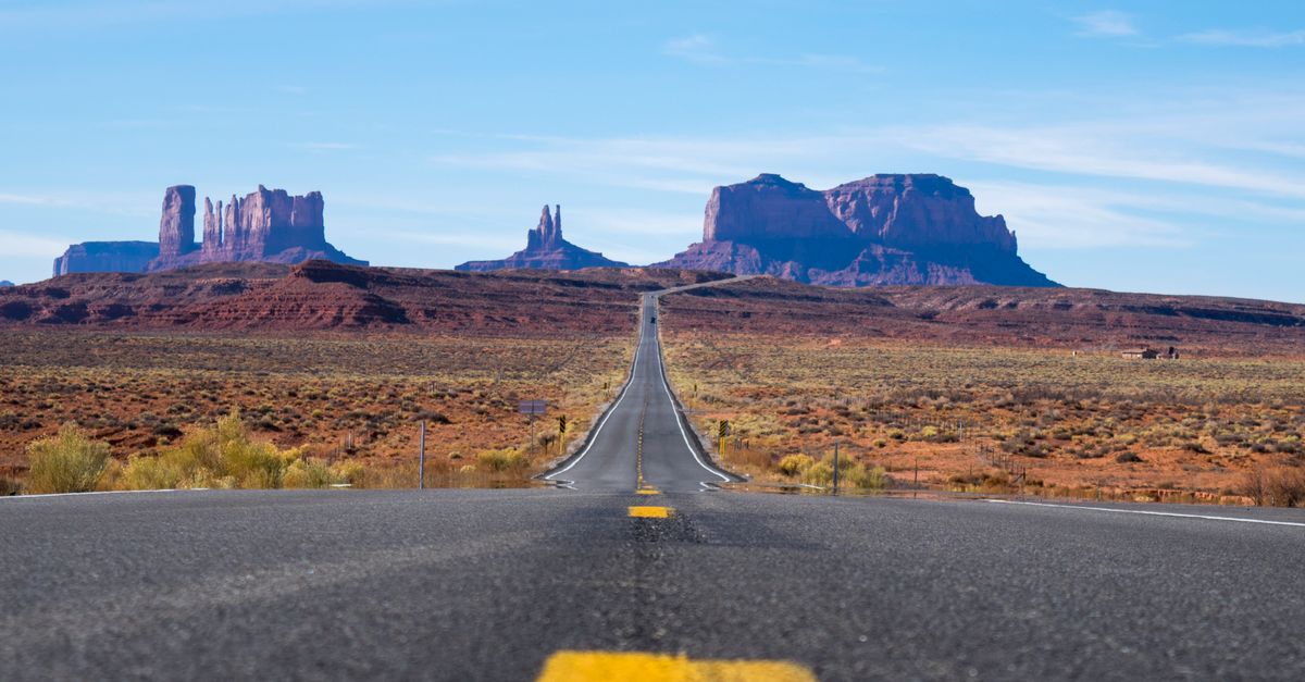 Rüyada Uzak Mesafe İlişkisinde Sevgiliyi Özlemek - Rüya Tabiri ve Anlamı - A straight highway leads through the iconic Monument Valley under a clear blue sky.