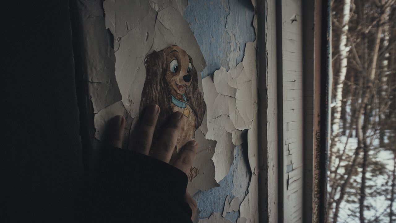 a human hand touching an old wall with peeling paint and a cartoon dog