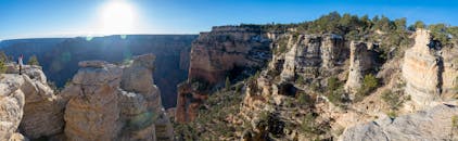 明媚的阳光下，徒步旅行者站在悬崖边缘，眺望大峡谷全景