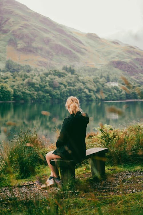 Woman Sitting on Bench Near Body of Water