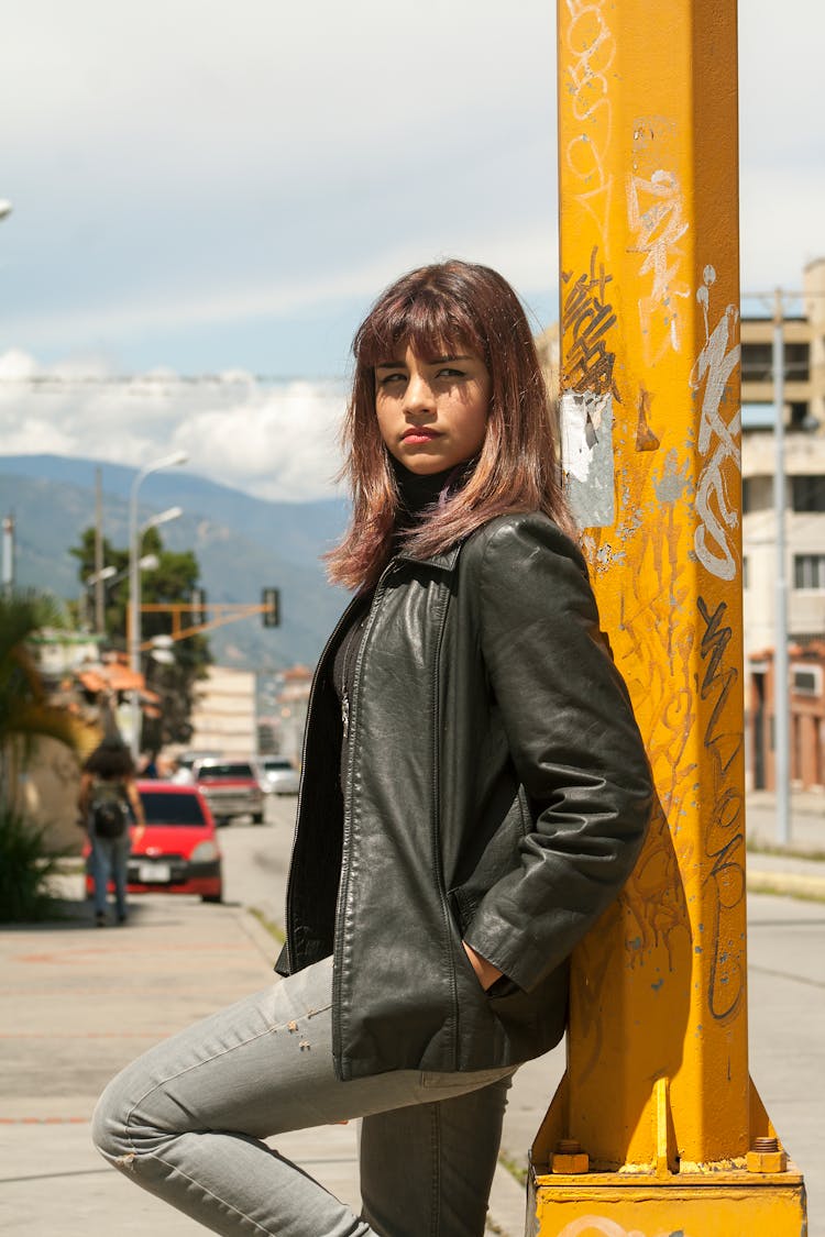 Teenage Girl In Black Leather Jacket Leaning Against A Post