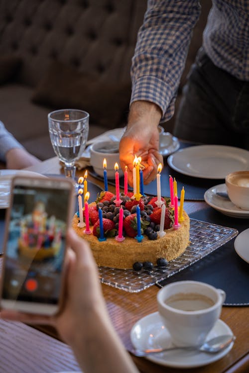 Person lighting Candles on a Cake 