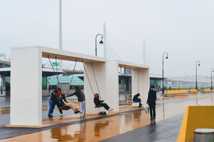 People Swinging On Swings In Rain