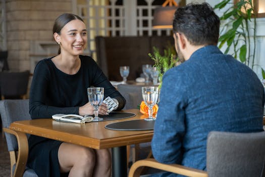 Two adults enjoying a casual conversation over drinks at a stylish restaurant.