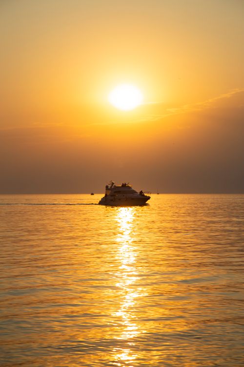 Free A serene sunset over the sea in Anapa, Russia, featuring a yacht silhouette against the golden sky. Stock Photo