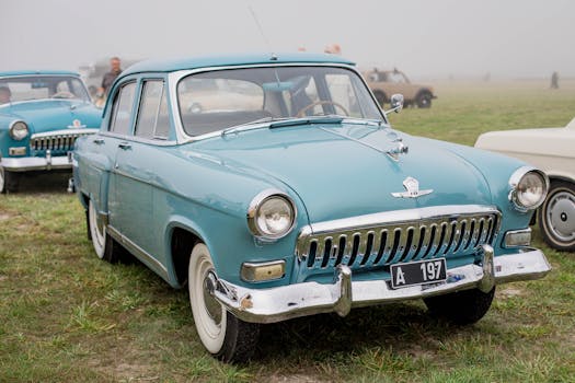 A retro blue Gaz M21 Volga on display at an outdoor vintage car show.