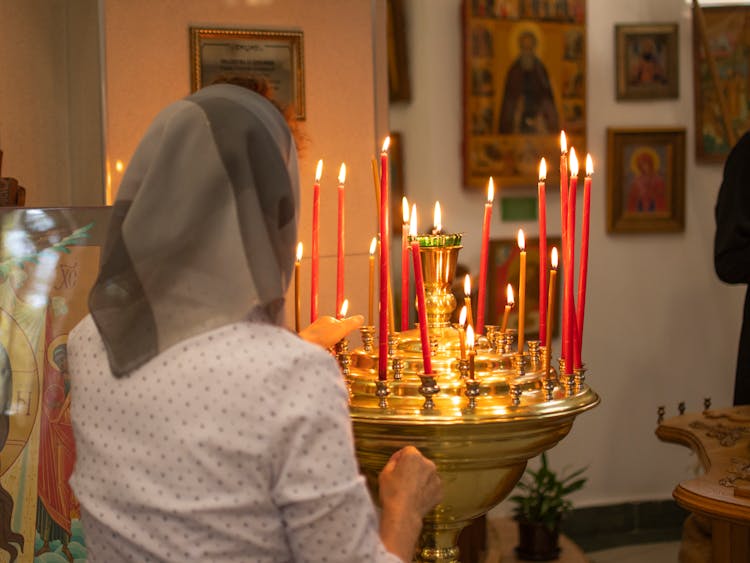 Back View Of A Woman Lighting Candles In Church 