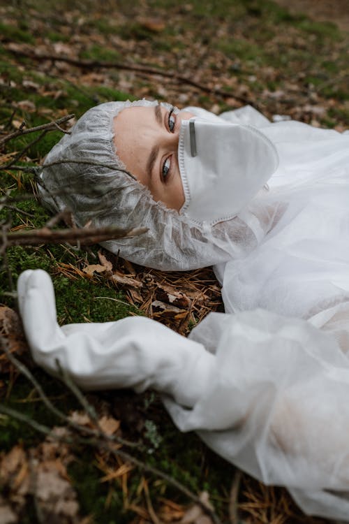 Woman in Personal Protective Equipment Lying on Grass