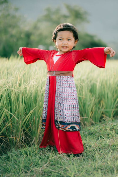 Girl in Traditional Clothes on Grass Field 