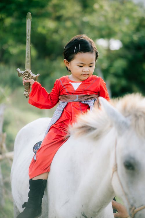 A Child Riding a White Pony Holding a Toy Sword