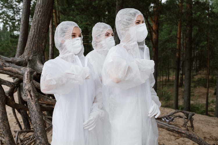 Three People Wearing White Hazmat Suits