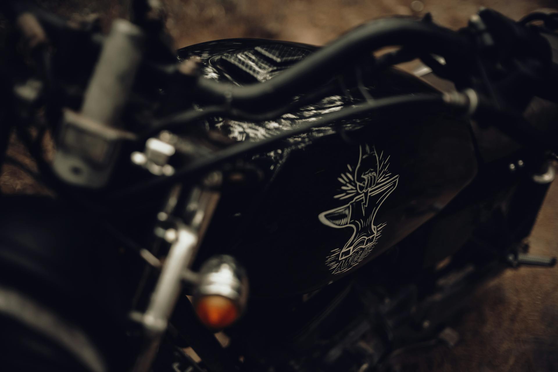 Close-up of a vintage motorcycle featuring a unique artistic sticker on the fuel tank.