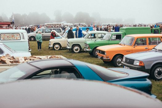 A vibrant gathering showcasing classic cars with enthusiastic crowds on a foggy day.