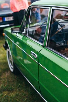 Close-up view of a vintage green car in an outdoor setting showcasing classic design elements.