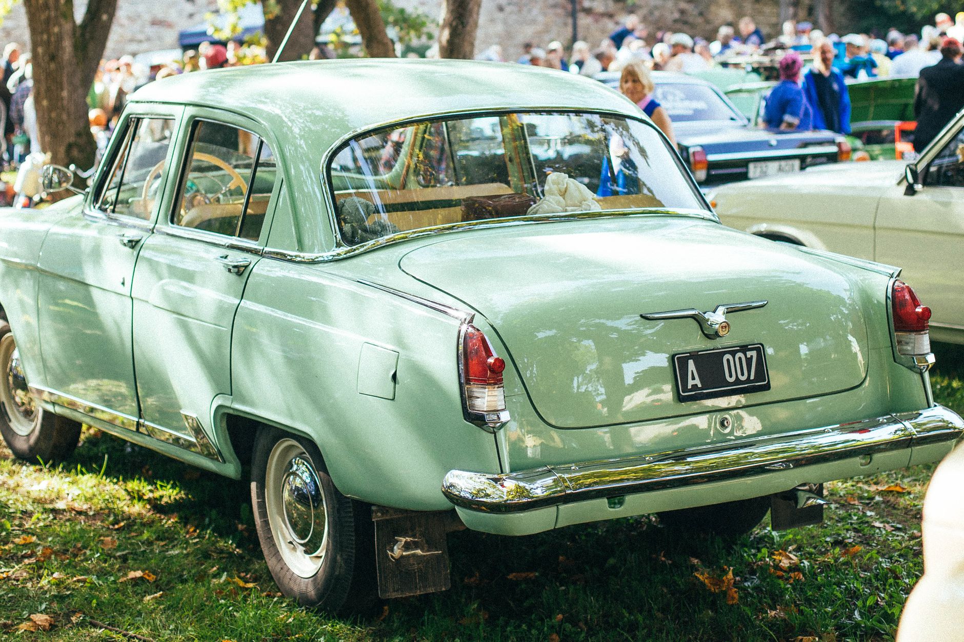 Light green vintage car showcased at an outdoor classic car event.