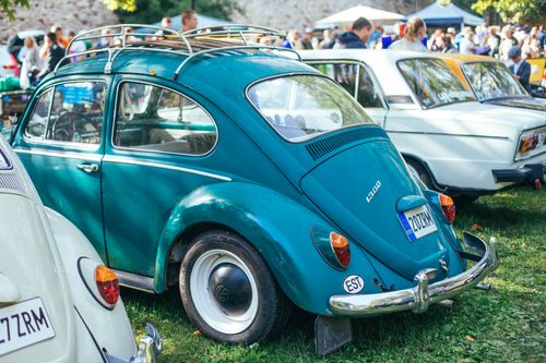 Free A teal Volkswagen Beetle displayed outdoors at a lively classic car show. Stock Photo
