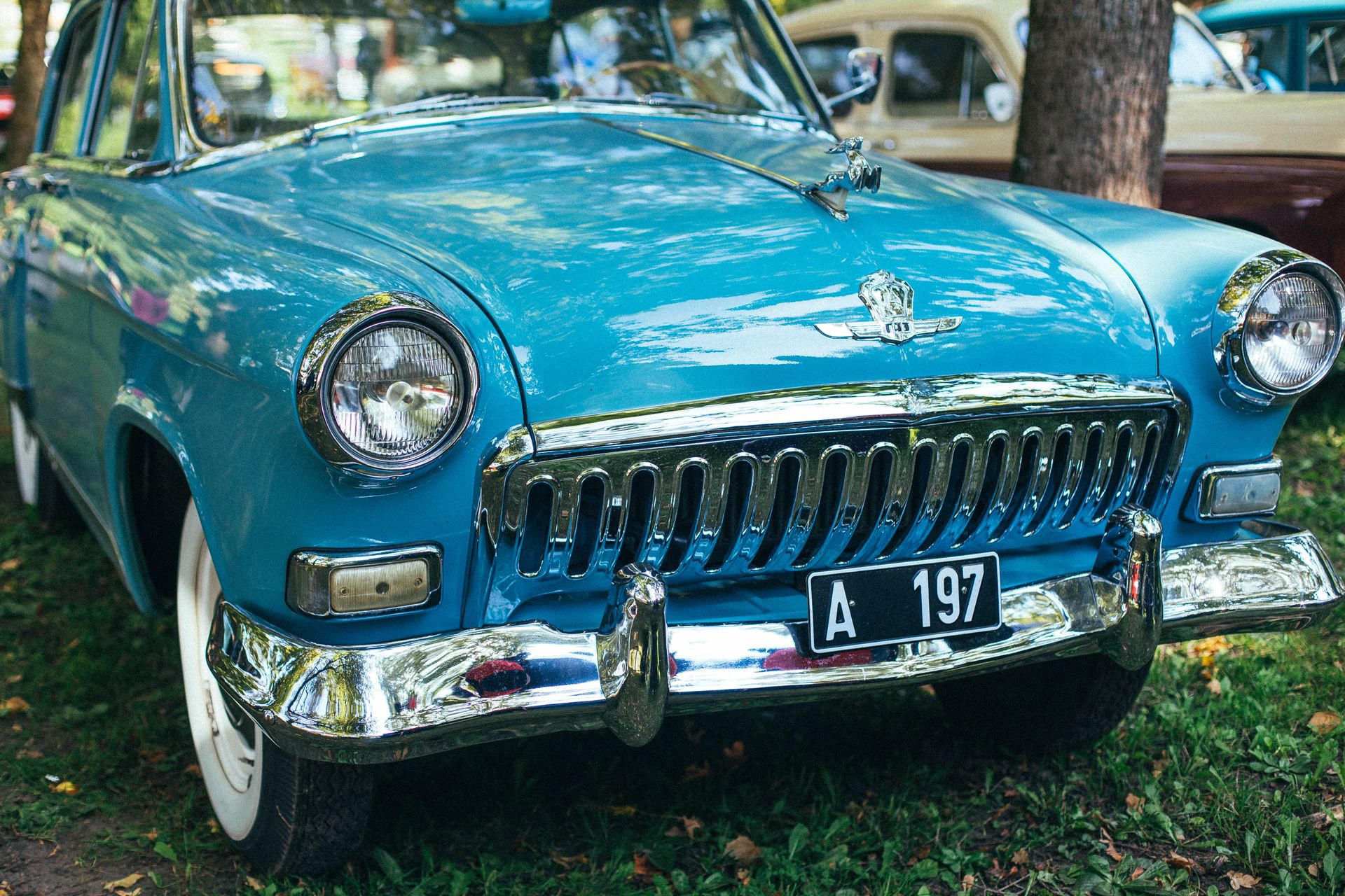 A classic blue vintage car with chrome details at an outdoor car show.