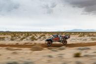 High-speed off-road truck racing through desert terrain, showcasing motion and adventure.