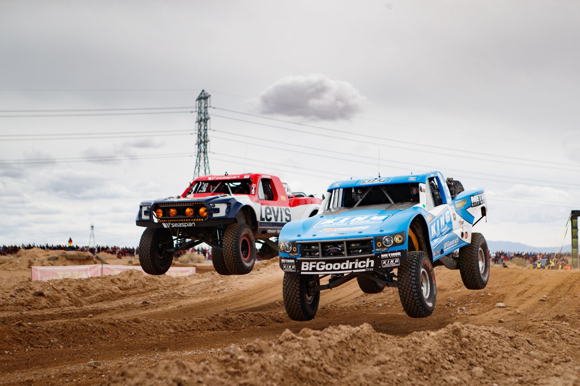 Dynamic off-road race with trucks soaring over desert terrain during a thrilling motorsport event.